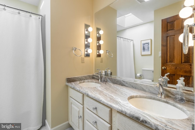 bathroom featuring a skylight, a shower with shower curtain, vanity, and toilet