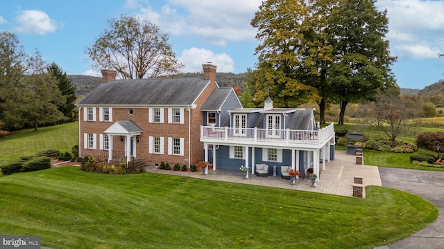 view of front of property featuring a balcony, a front lawn, and a patio