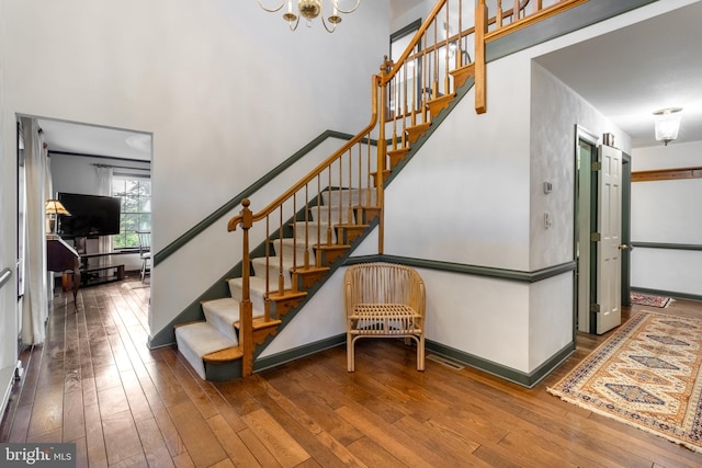 stairs with wood-type flooring and a notable chandelier