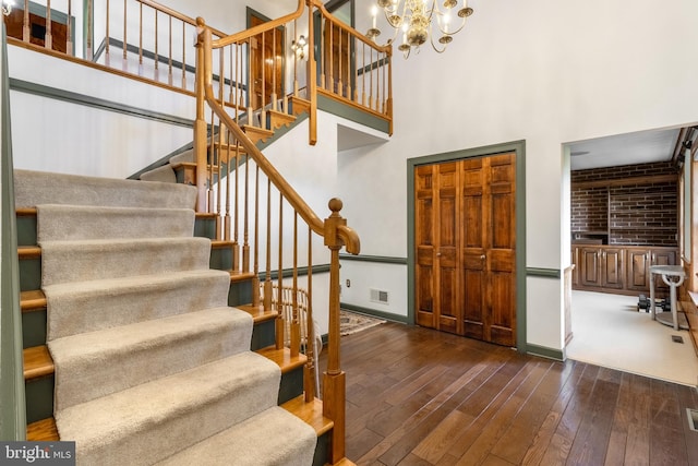 foyer entrance with a towering ceiling, dark wood-type flooring, and a chandelier