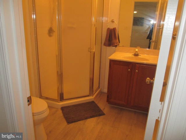 bathroom featuring vanity, toilet, wood-type flooring, and walk in shower