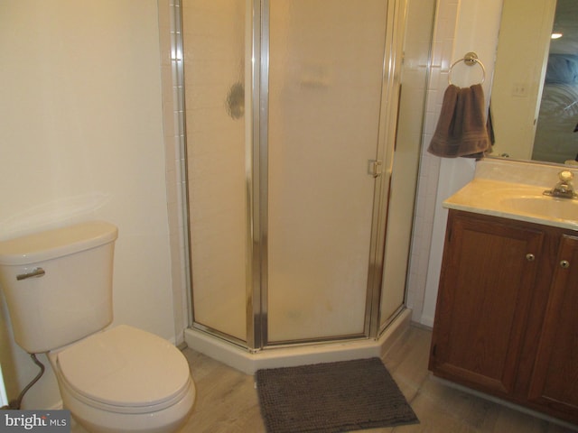 bathroom featuring vanity, hardwood / wood-style flooring, toilet, and a shower with shower door