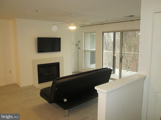 carpeted living room featuring ceiling fan and a tiled fireplace