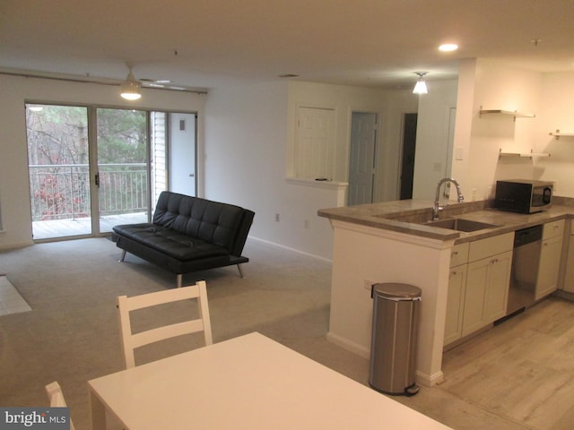 kitchen featuring kitchen peninsula, stainless steel appliances, light colored carpet, sink, and white cabinetry