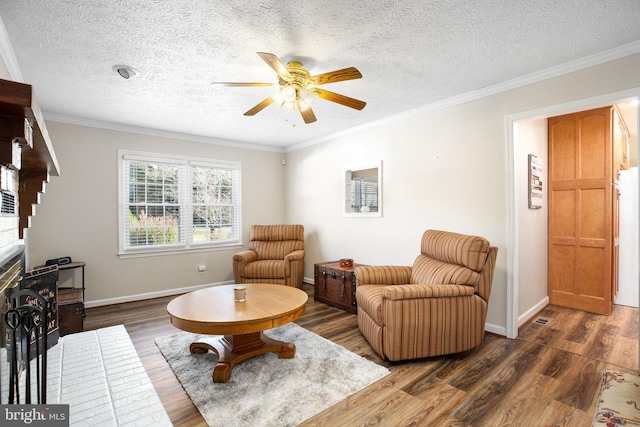 living room with ceiling fan, a textured ceiling, dark hardwood / wood-style flooring, and ornamental molding