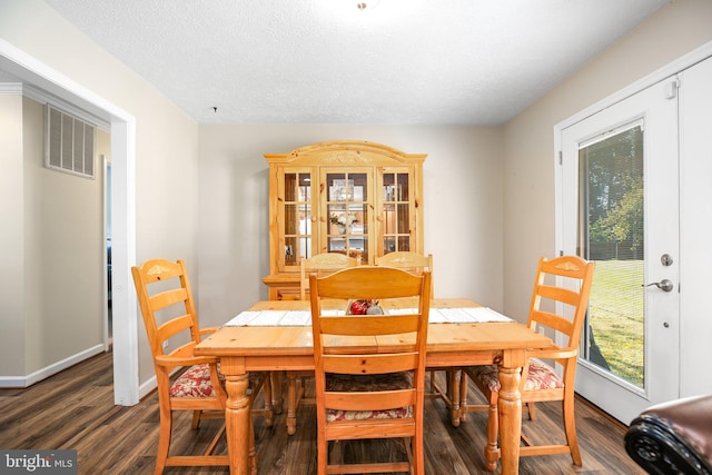 dining area with a textured ceiling and dark hardwood / wood-style flooring