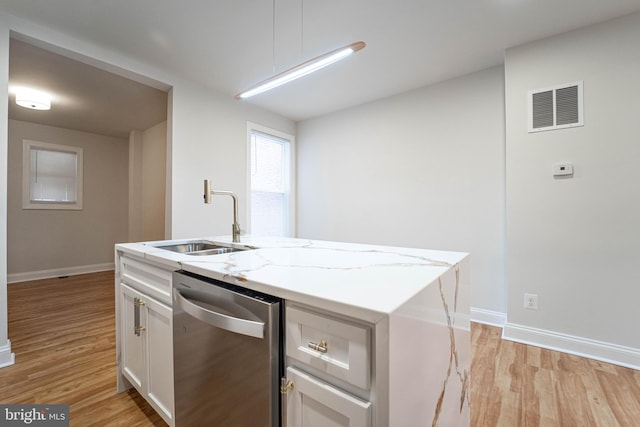 kitchen with dishwasher, a kitchen island with sink, white cabinetry, light stone counters, and light wood-type flooring