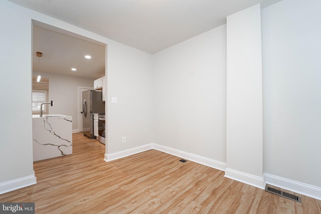 unfurnished room featuring sink and light hardwood / wood-style floors