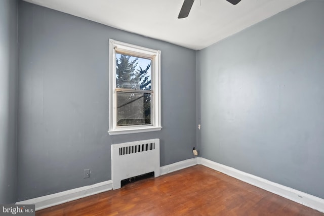 unfurnished room with dark wood-type flooring, ceiling fan, and radiator