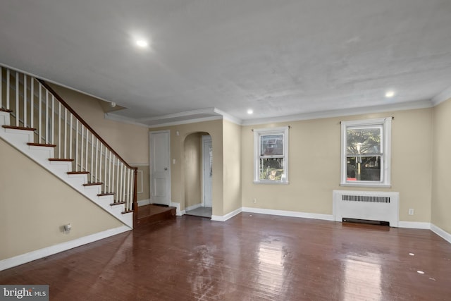 unfurnished living room with dark wood-type flooring, crown molding, and radiator