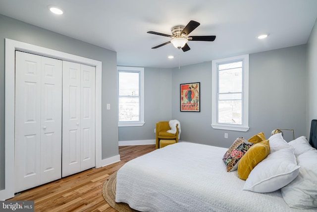 bedroom with a closet, multiple windows, hardwood / wood-style flooring, and ceiling fan