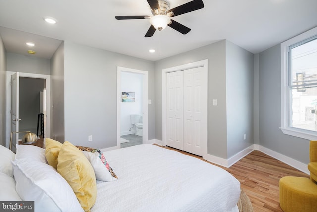 bedroom with ensuite bathroom, light hardwood / wood-style flooring, ceiling fan, and a closet