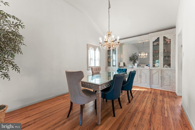 dining area with lofted ceiling, a chandelier, and wood-type flooring