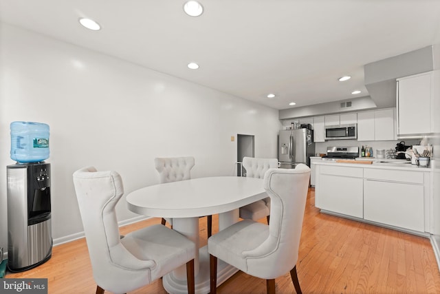 dining space with light wood-type flooring and sink