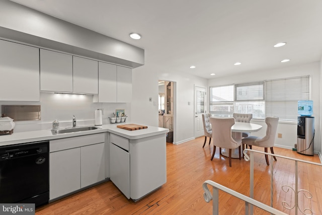 kitchen featuring light wood-type flooring, white cabinets, sink, kitchen peninsula, and dishwasher