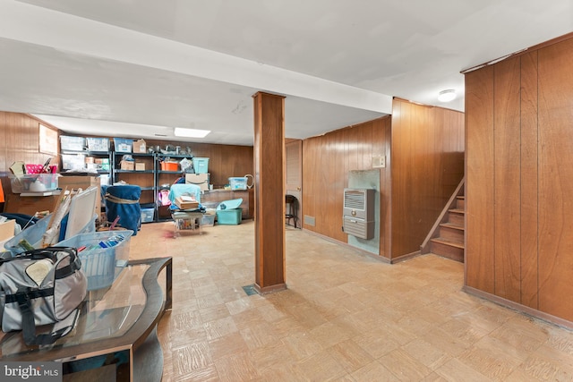 basement featuring wood walls and heating unit