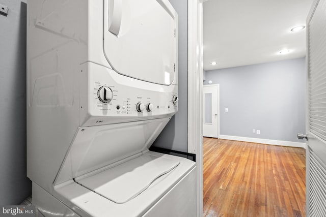 laundry room featuring stacked washer / drying machine and hardwood / wood-style floors