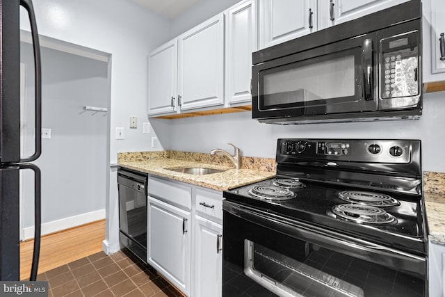 kitchen featuring sink, light stone counters, dark hardwood / wood-style floors, black appliances, and white cabinetry