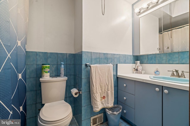 bathroom featuring tile patterned floors, toilet, tile walls, and vanity