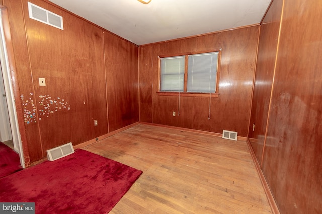 empty room with wood walls and light hardwood / wood-style floors