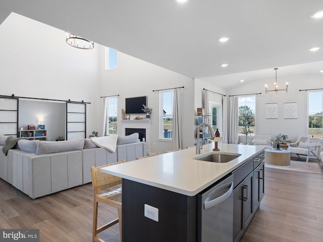 kitchen with a kitchen island with sink, sink, a barn door, light hardwood / wood-style flooring, and decorative light fixtures