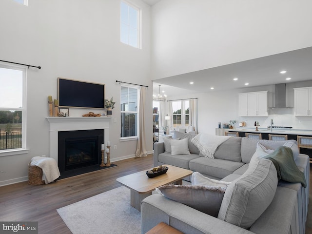 living room with an inviting chandelier, sink, dark wood-type flooring, and a high ceiling