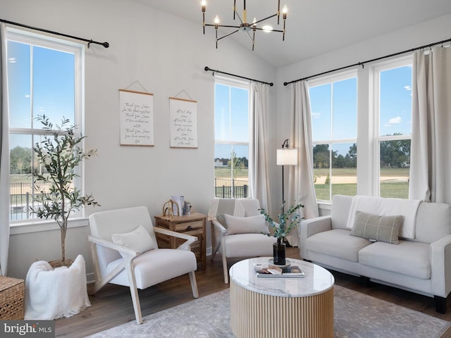 living room with a chandelier, vaulted ceiling, and wood-type flooring