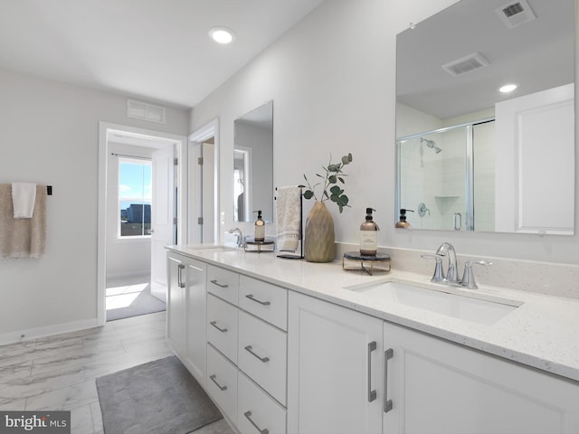 bathroom featuring a shower with shower door and vanity