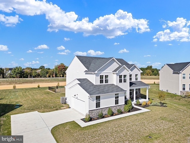 view of front of home with central air condition unit, a garage, and a front yard