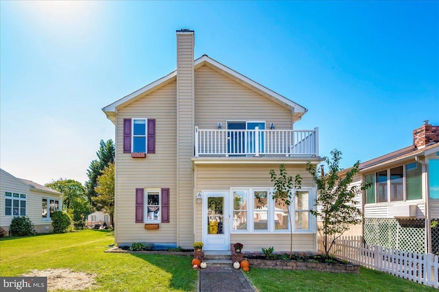 back of house with a yard and a balcony