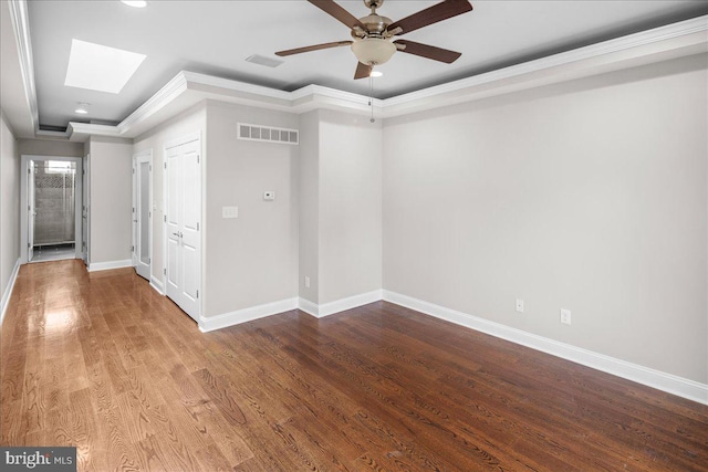 empty room with wood-type flooring, a skylight, crown molding, and ceiling fan