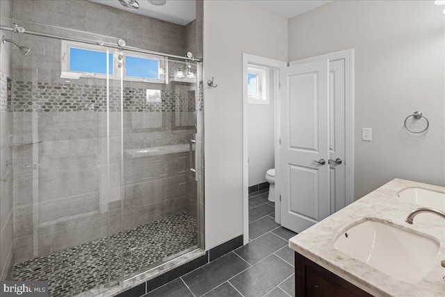 bathroom with a healthy amount of sunlight, vanity, toilet, and a shower with shower door