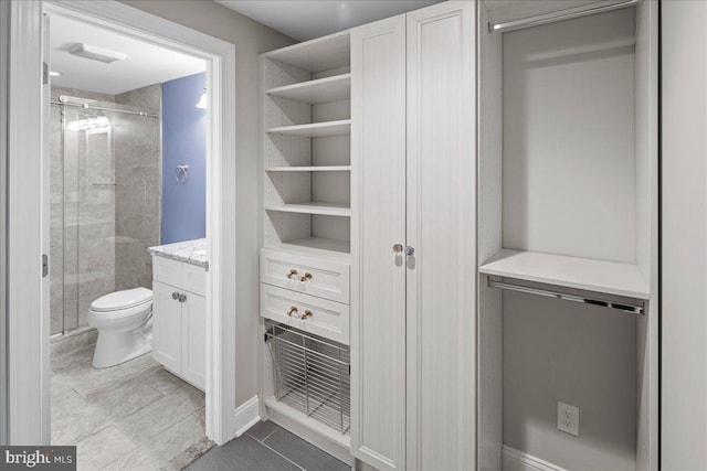 bathroom featuring walk in shower, vanity, tile patterned flooring, and toilet