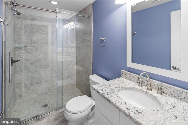 bathroom with vanity, a shower with shower door, and toilet