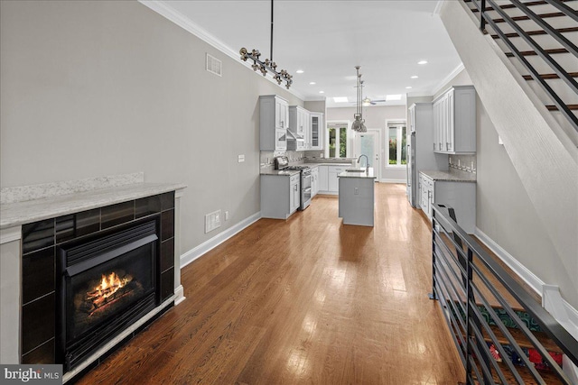 kitchen with dark hardwood / wood-style flooring, crown molding, a center island, and stainless steel stove