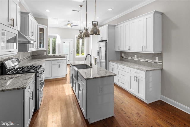 kitchen featuring a kitchen island with sink, hardwood / wood-style floors, sink, appliances with stainless steel finishes, and decorative light fixtures