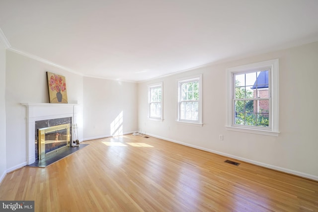 unfurnished living room with light hardwood / wood-style flooring, ornamental molding, and a premium fireplace