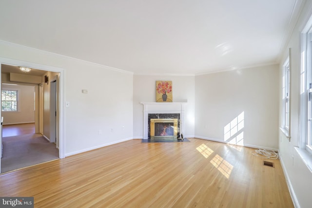 unfurnished living room featuring light hardwood / wood-style floors, crown molding, and a premium fireplace