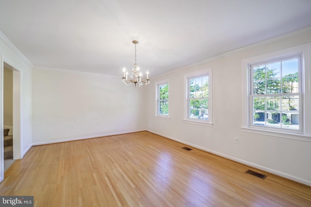 empty room featuring light hardwood / wood-style flooring, a healthy amount of sunlight, and an inviting chandelier