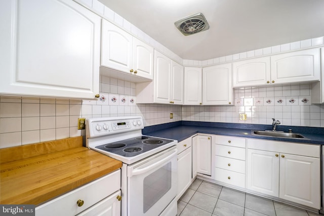 kitchen featuring white cabinetry, sink, light tile patterned floors, and white electric range