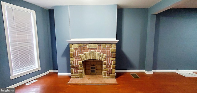 unfurnished living room featuring a stone fireplace and hardwood / wood-style floors