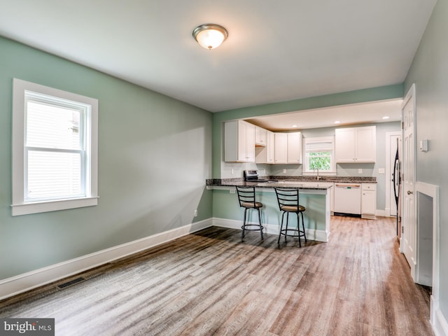 kitchen featuring white cabinetry, kitchen peninsula, a breakfast bar area, and dishwasher