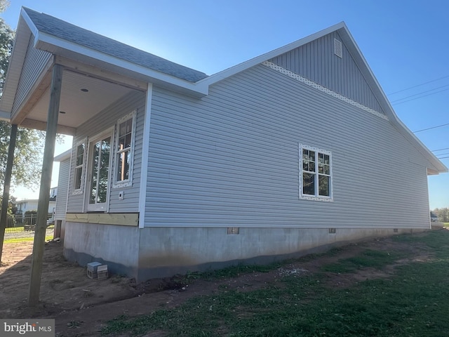 view of side of property with roof with shingles and crawl space