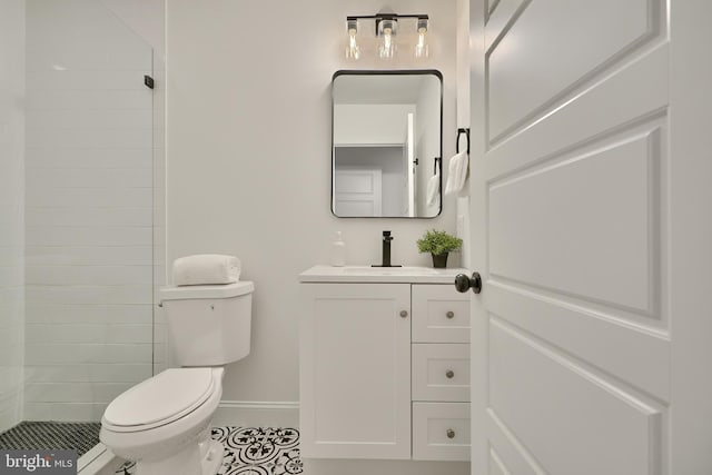 bathroom featuring vanity, a tile shower, toilet, and tile patterned flooring