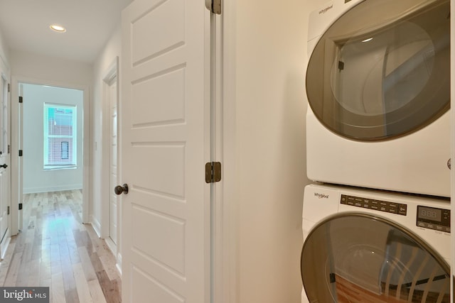 clothes washing area with light hardwood / wood-style floors and stacked washer and dryer