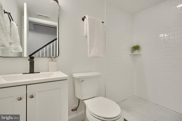 bathroom with vanity, toilet, and a tile shower