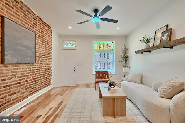 living room featuring brick wall, light hardwood / wood-style floors, and ceiling fan