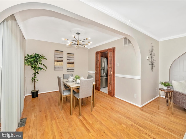 dining room with light hardwood / wood-style floors, crown molding, and an inviting chandelier