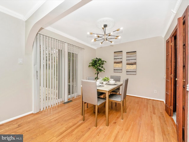 dining space featuring light hardwood / wood-style floors, ornamental molding, and a chandelier