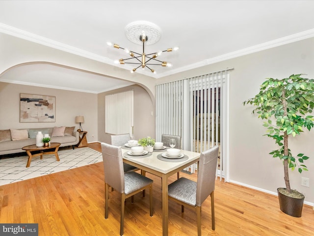 dining space with light hardwood / wood-style flooring, ornamental molding, and a notable chandelier